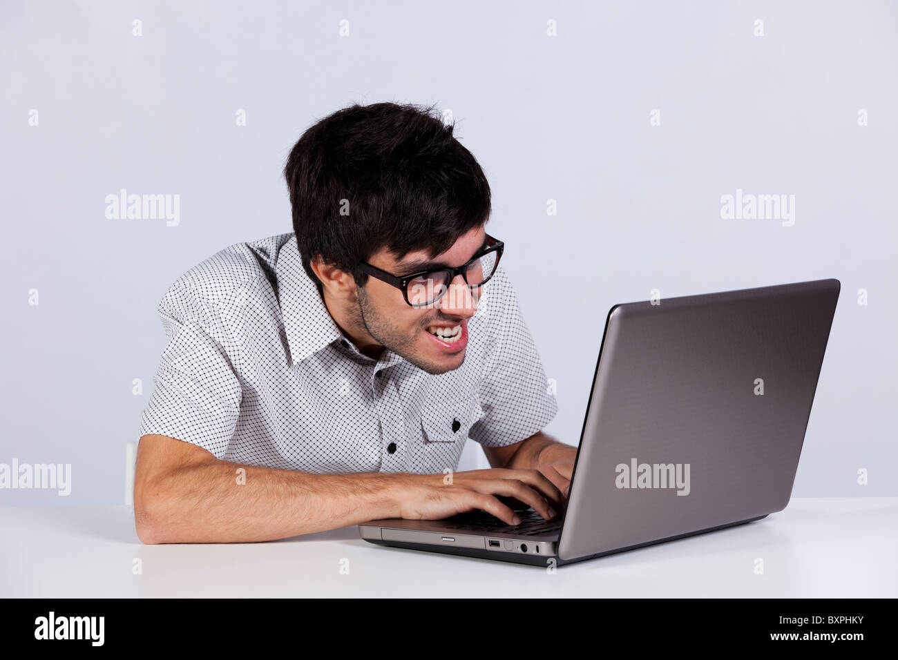 nerd-teenager-working-with-his-laptop-with-a-funny-face-BXPHKY.jpg