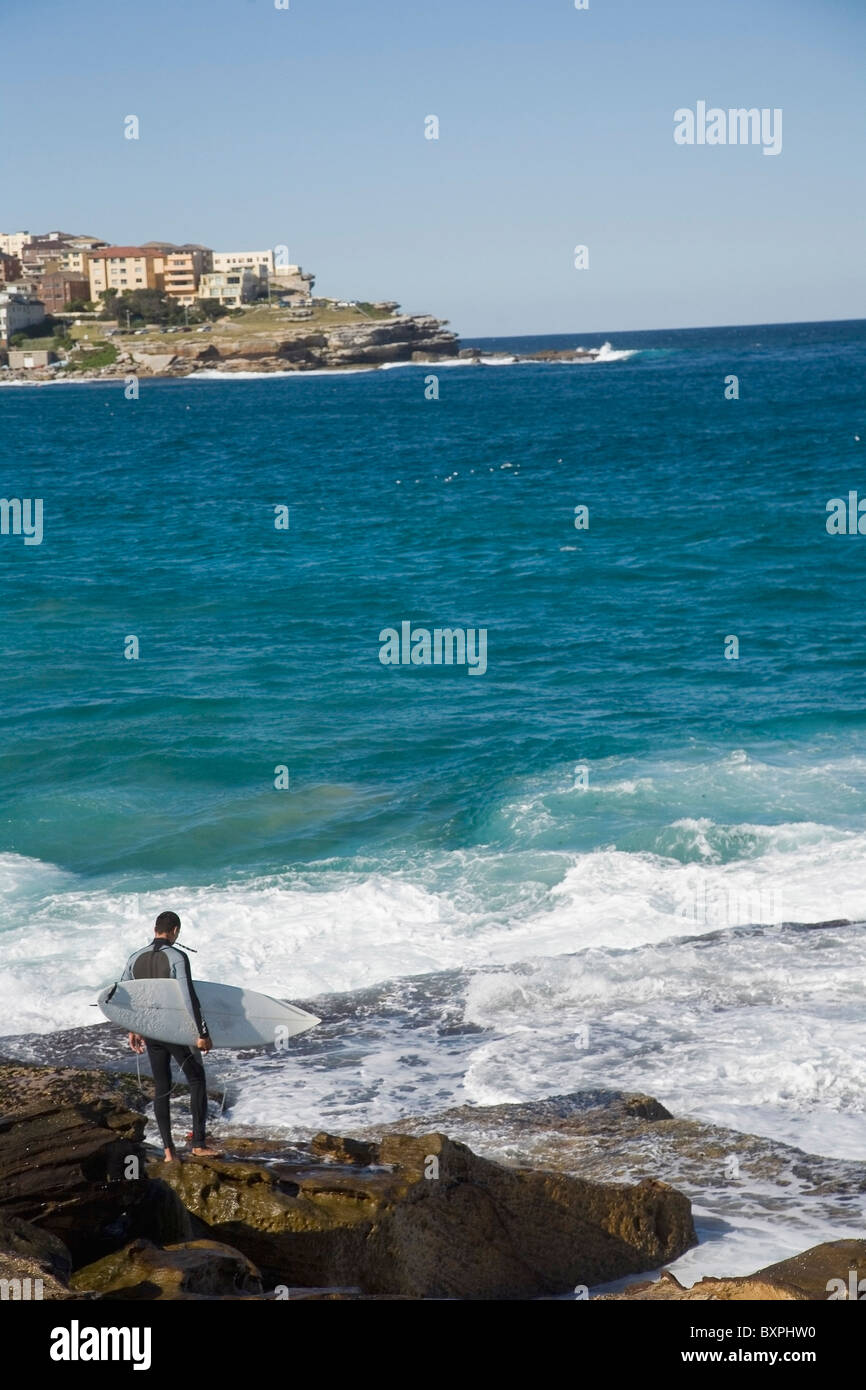 Male Surfer Standing On Rocks At Bondi Beach Stock Photo