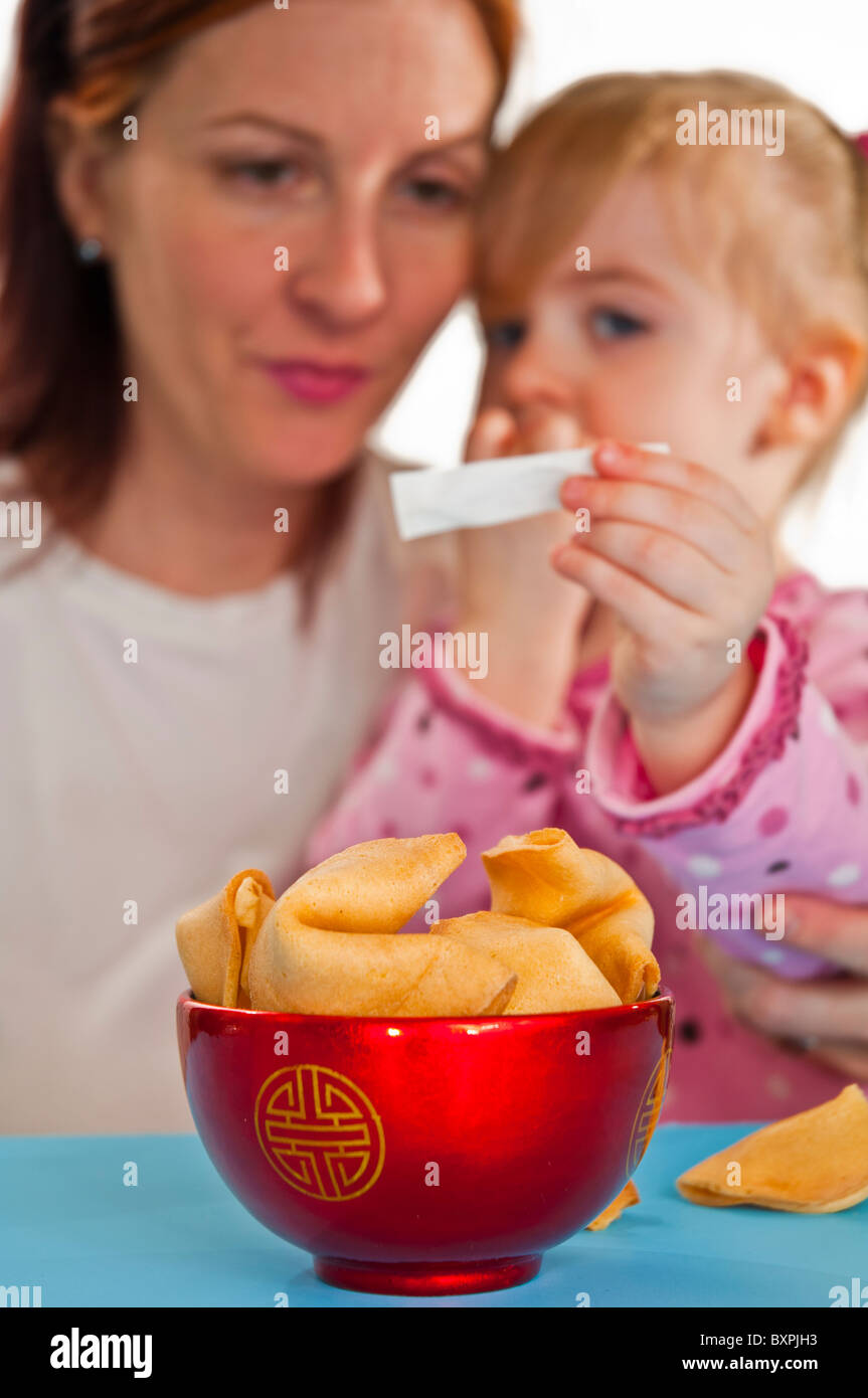Mother and daughter reading fortune message from a fortune cookie Stock