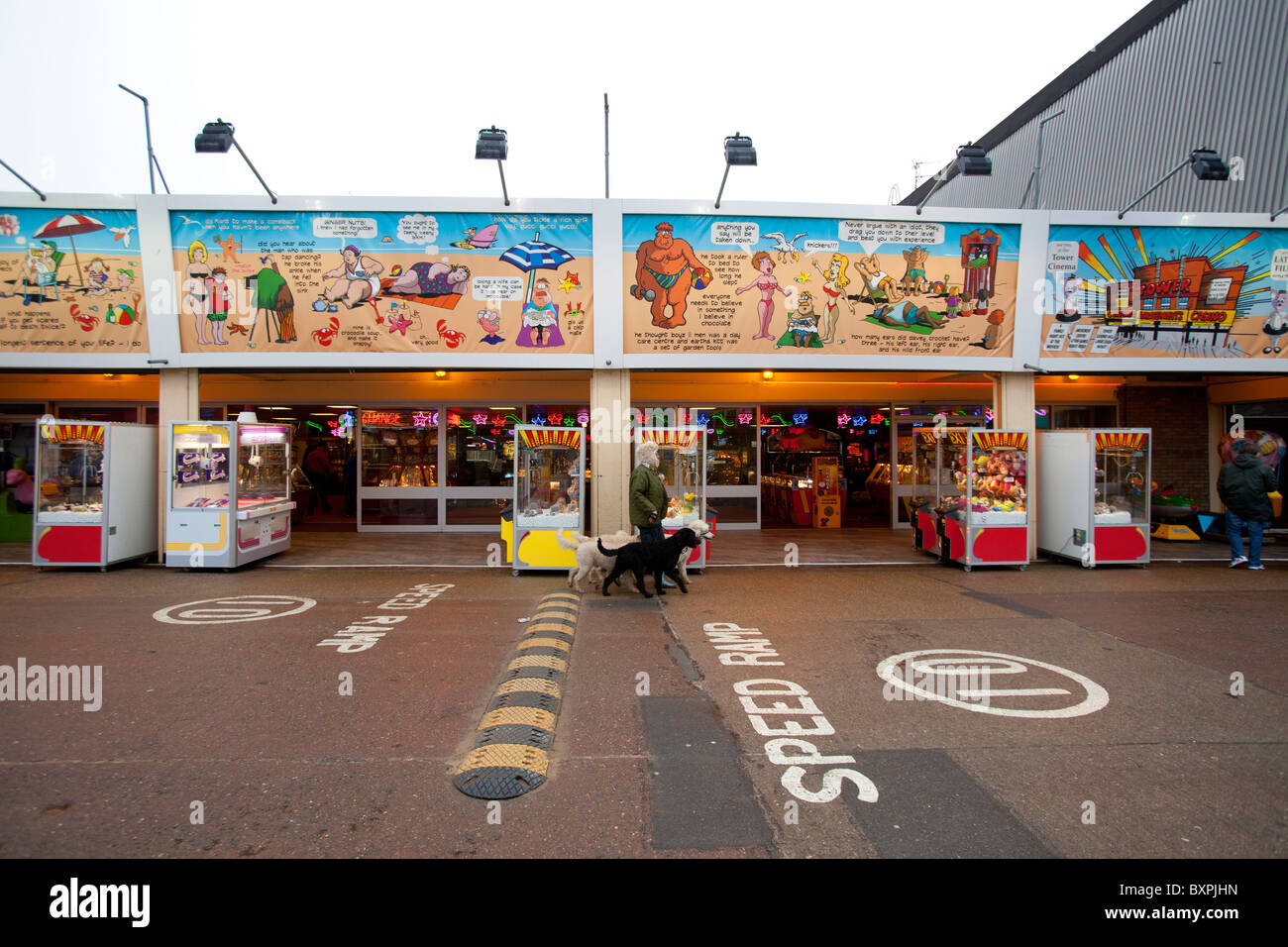 Skegness, Lincolnshire, UK.Skegness, Lincolnshire, UK. A woman walks her dogs in front of amusements in Skegness. Stock Photo
