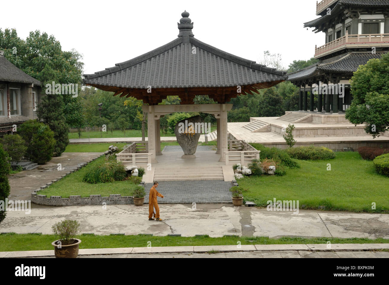 A lone Monk walking in the gardens Da Ming Buddhist temple in Yangzhou Jiangsu Province of China Stock Photo
