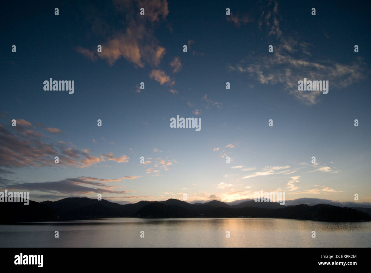 Dawn light illuminates the hills around Orokawa Bay in New Zealand's ...