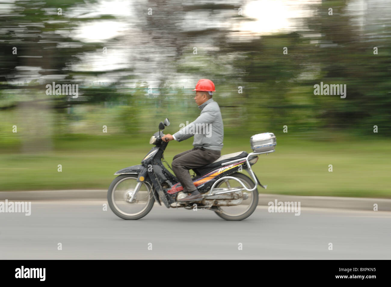 A Chinese wearing a helmet on a motorbike Stock Photo