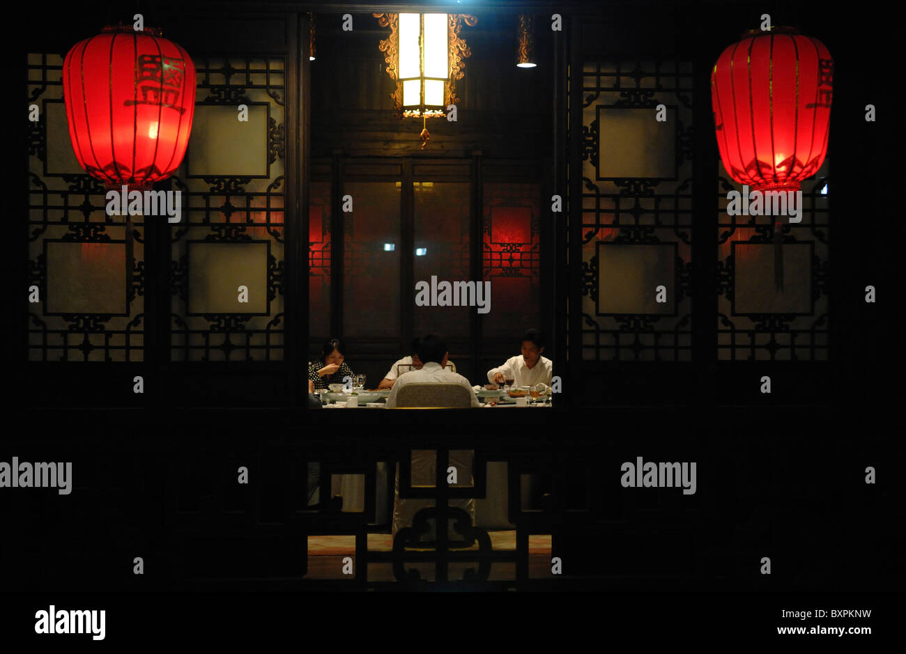 A group of people eating a traditional Chinese meal in a old historic traditional building with lanterns Stock Photo