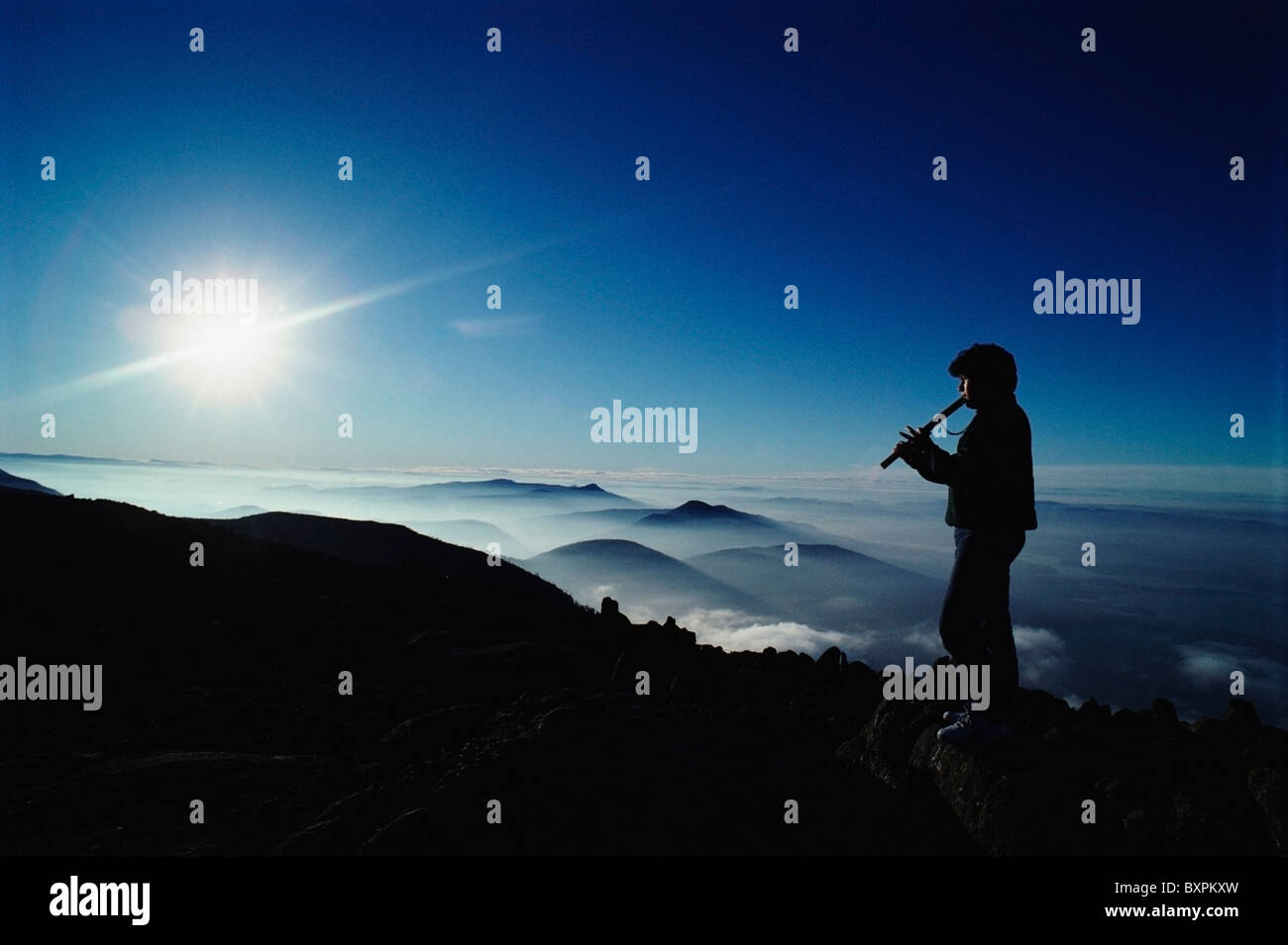 Man Playing Flute Above Mountains Stock Photo