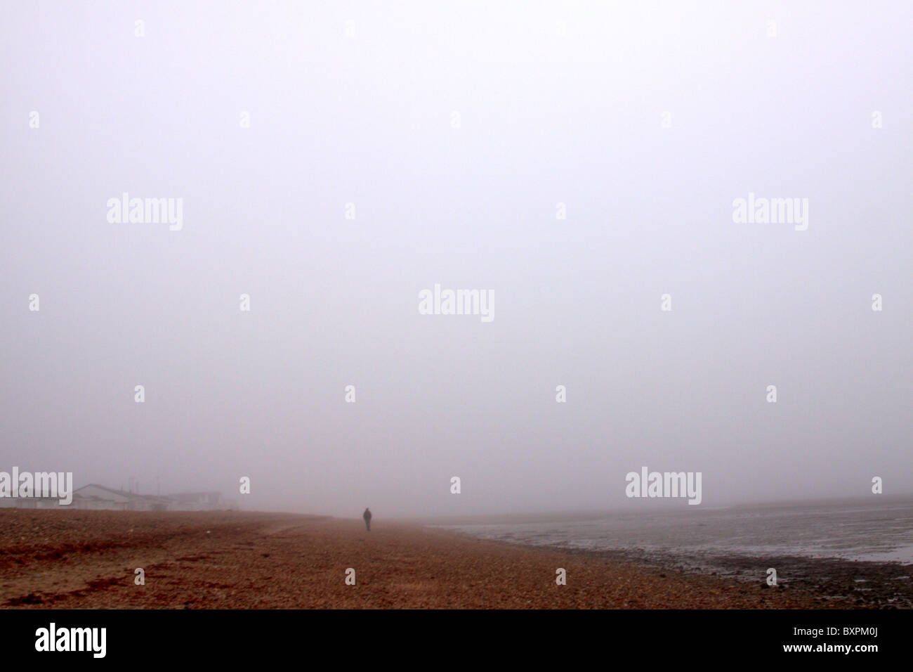 Lone figure walks alone a beach in fog Stock Photo - Alamy
