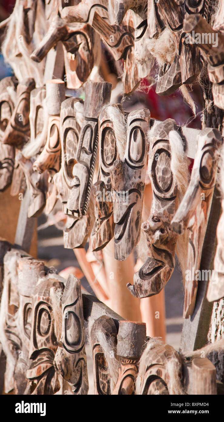 Row of traditionally carved wooden masks for sale at a souvenir store