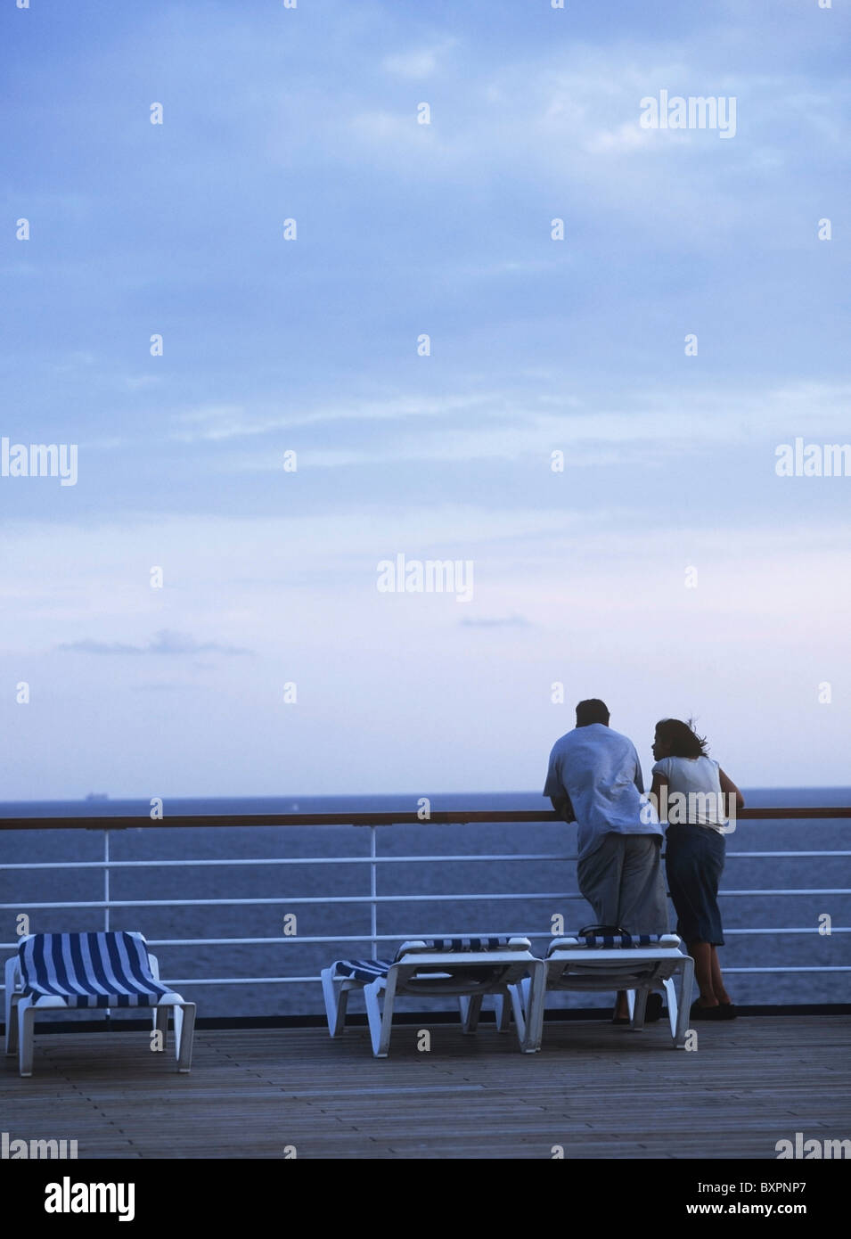 Couple Looking Out From Deck Of Cruise Ship At Dusk Stock Photo - Alamy