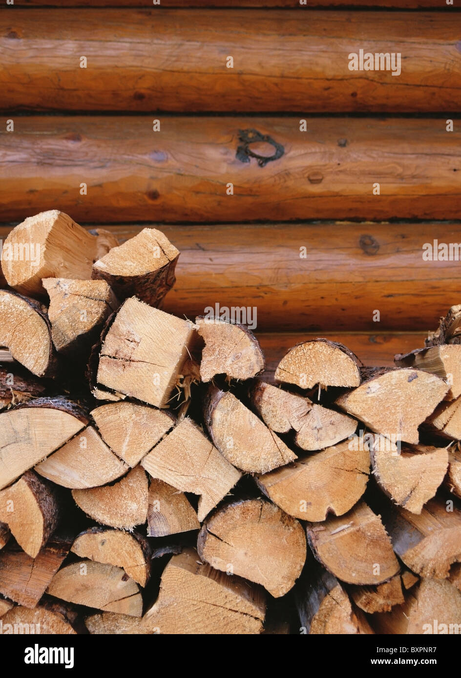 Logs stacked up in front of a log cabin hires stock photography and