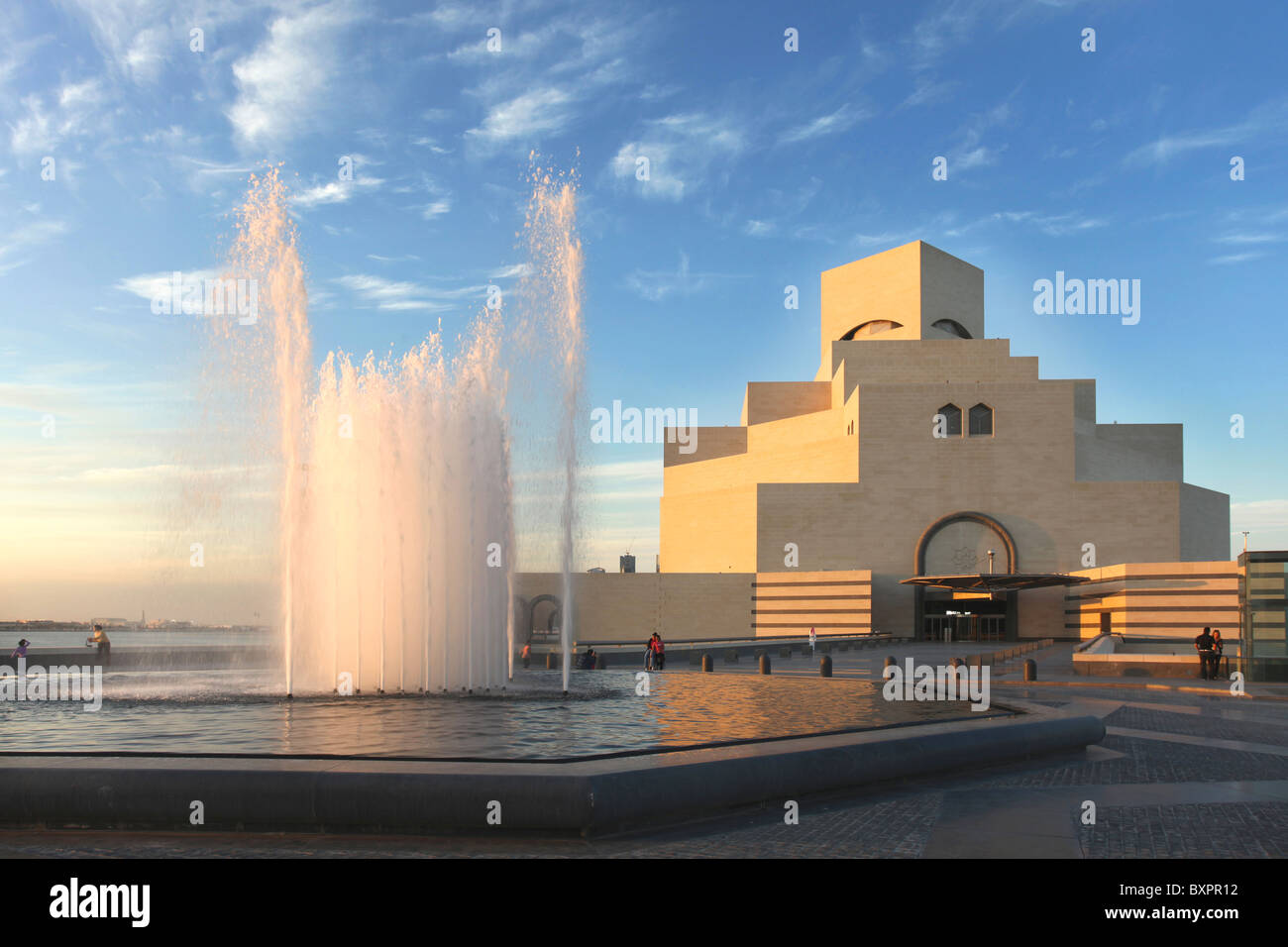 A view of the Museum of Islamic Art in Doha, Qatar, Arabia under a cloudy winter sky, with the water catching the evening sun. Stock Photo