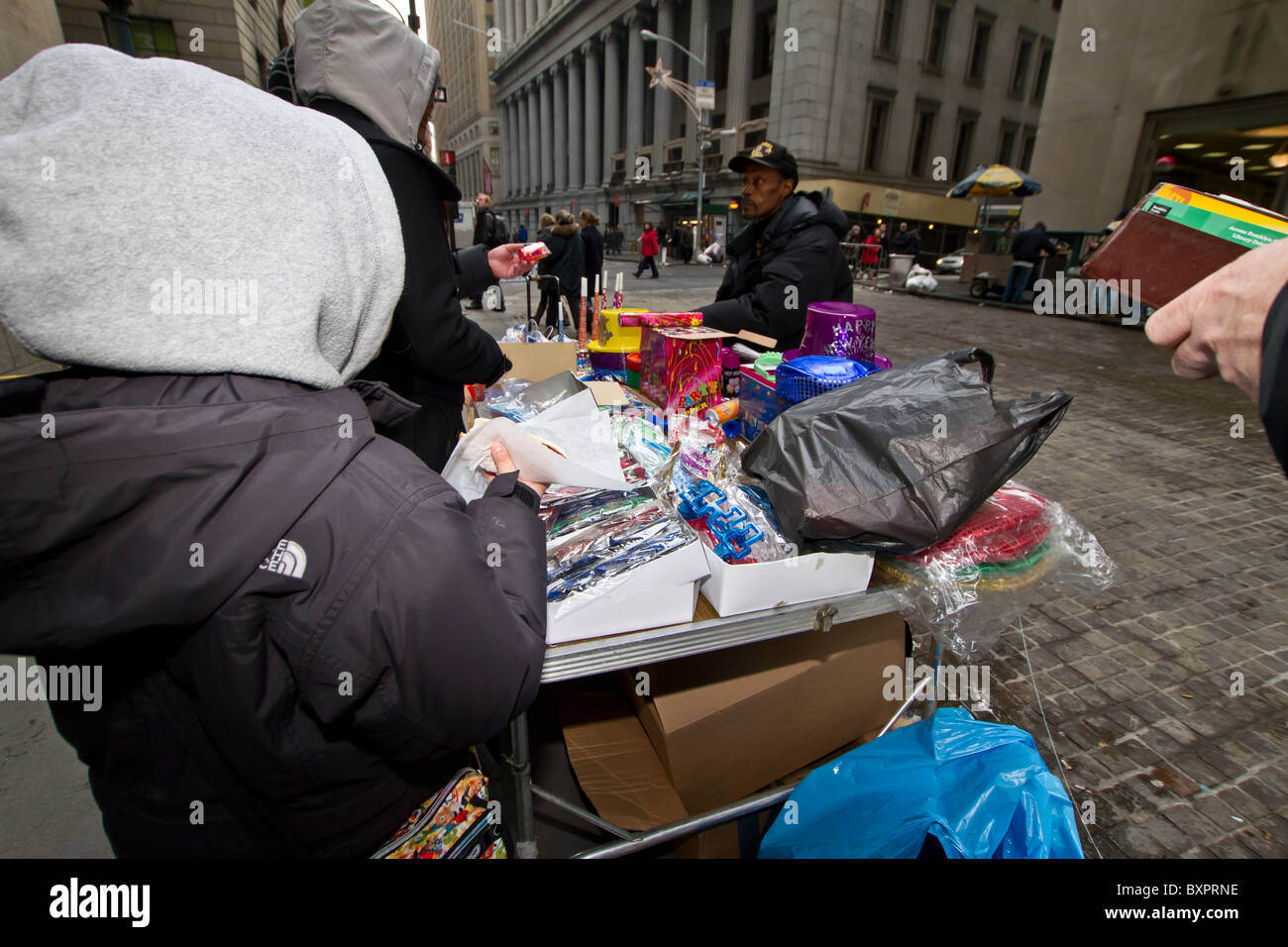 A sidewalk vendor sells hats, noisemakers, and other New Year's