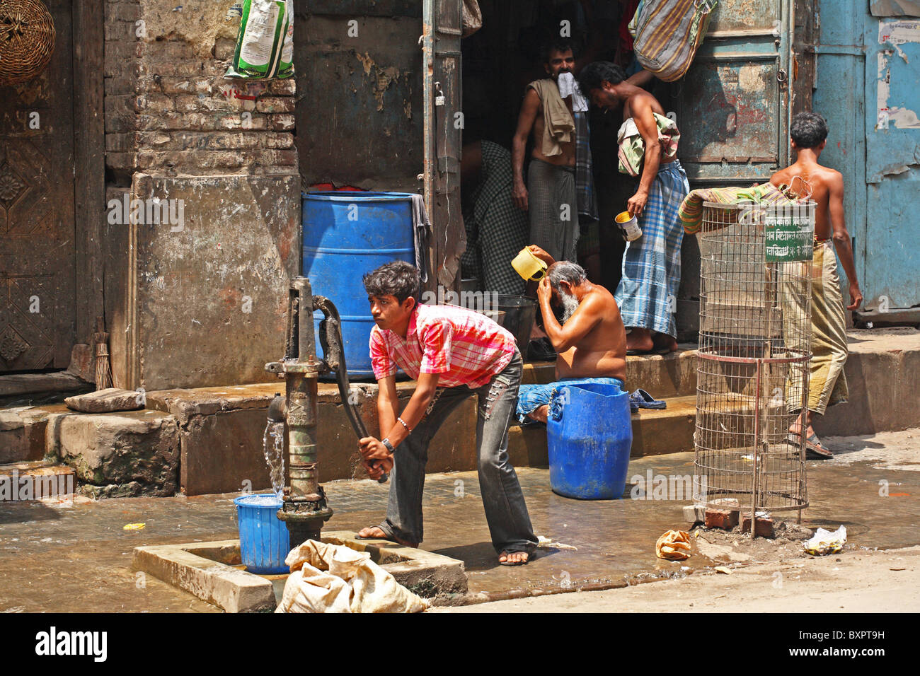 Boy using water fountain in street, Calcutta, India Stock Photo