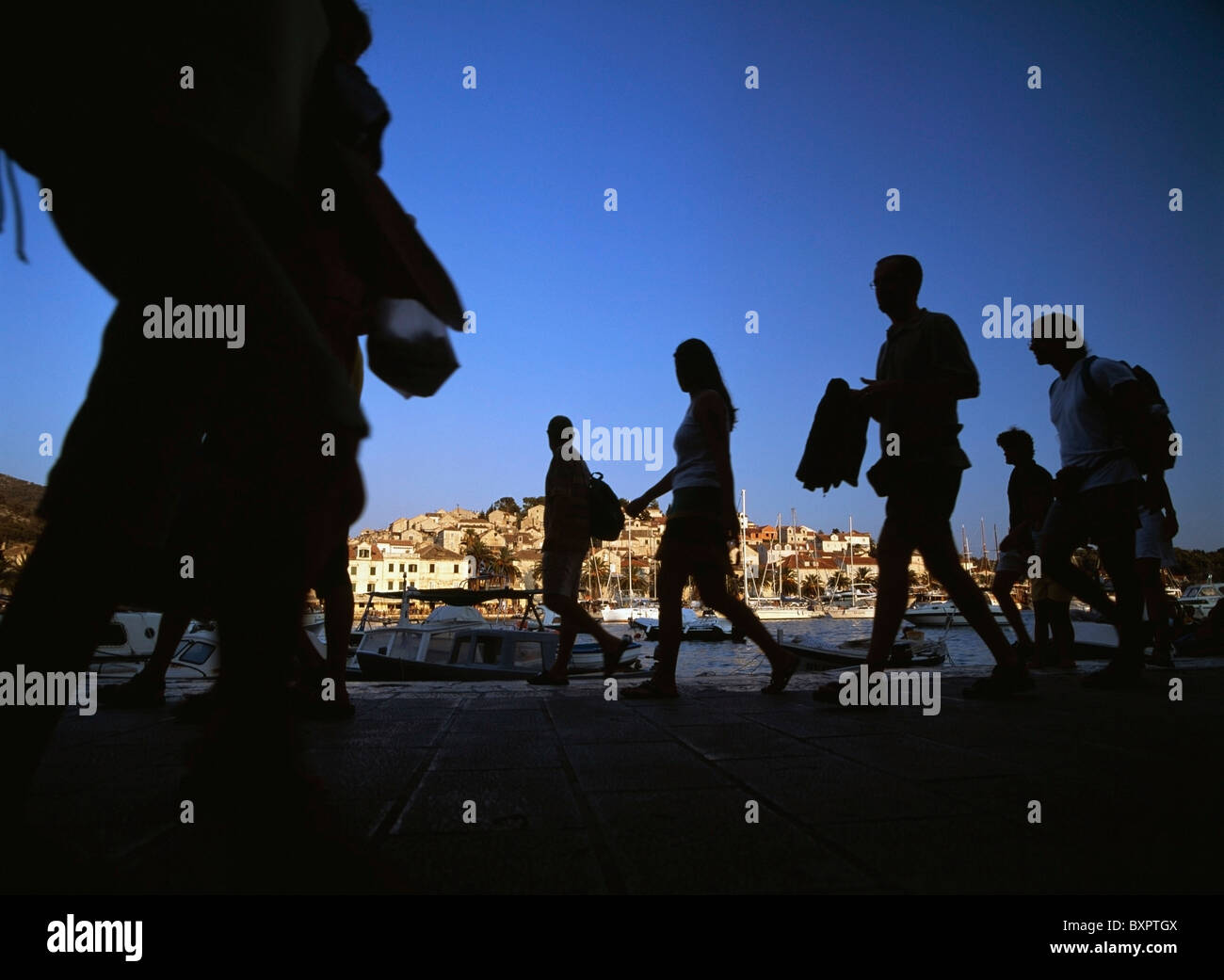 People Walking Along The Harbour-Front Of Hvar Town At Dusk Stock Photo