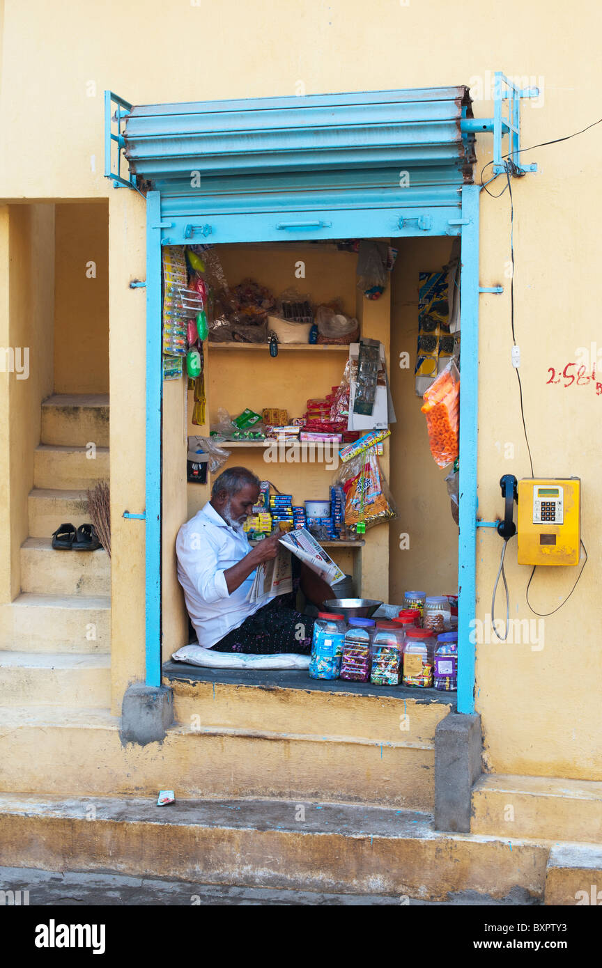 Indian man sitting reading inside a rural South Indian village shop. Andhra Pradesh, India Stock Photo