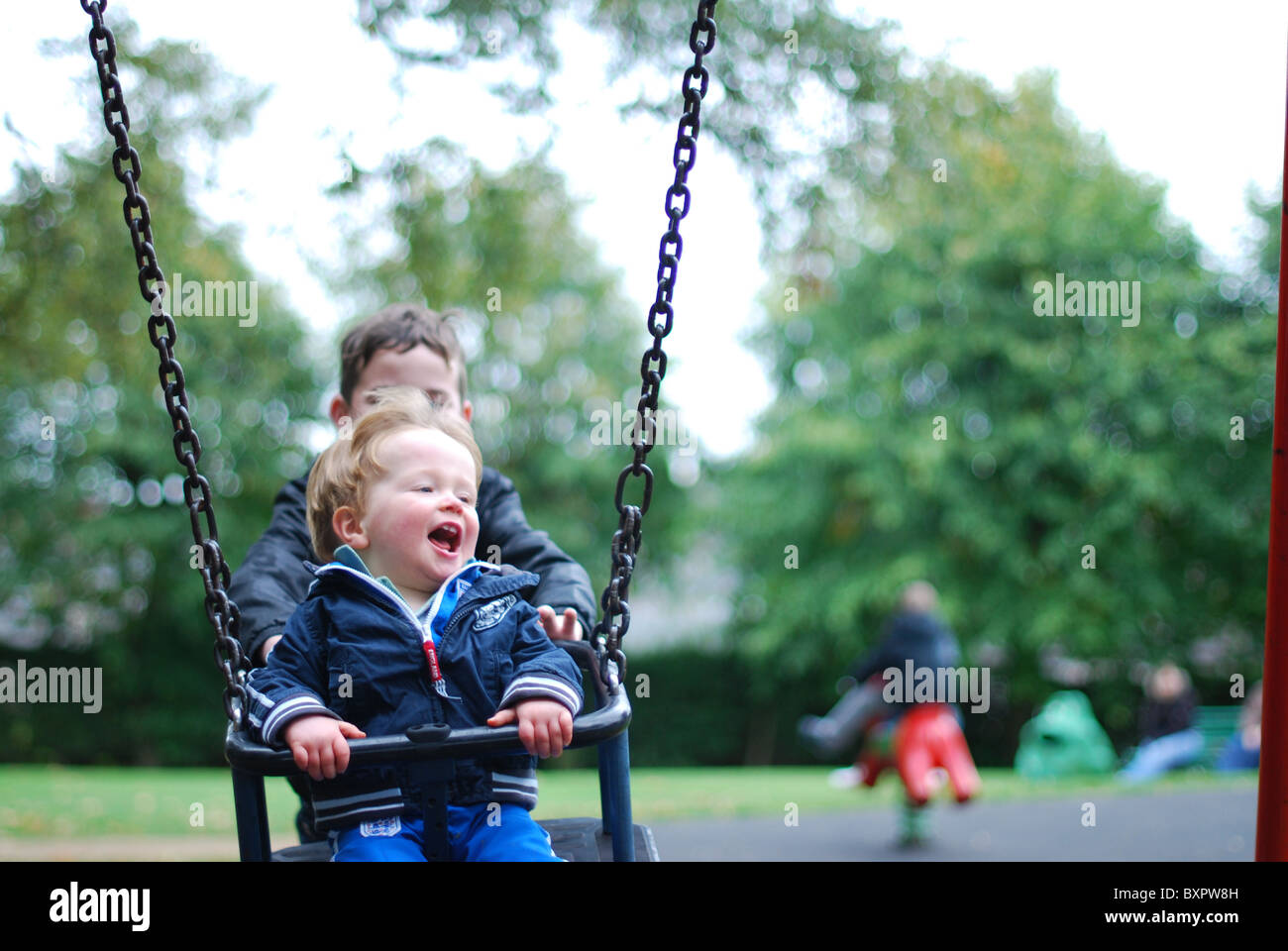 Child pushing another child on a swing Stock Photo