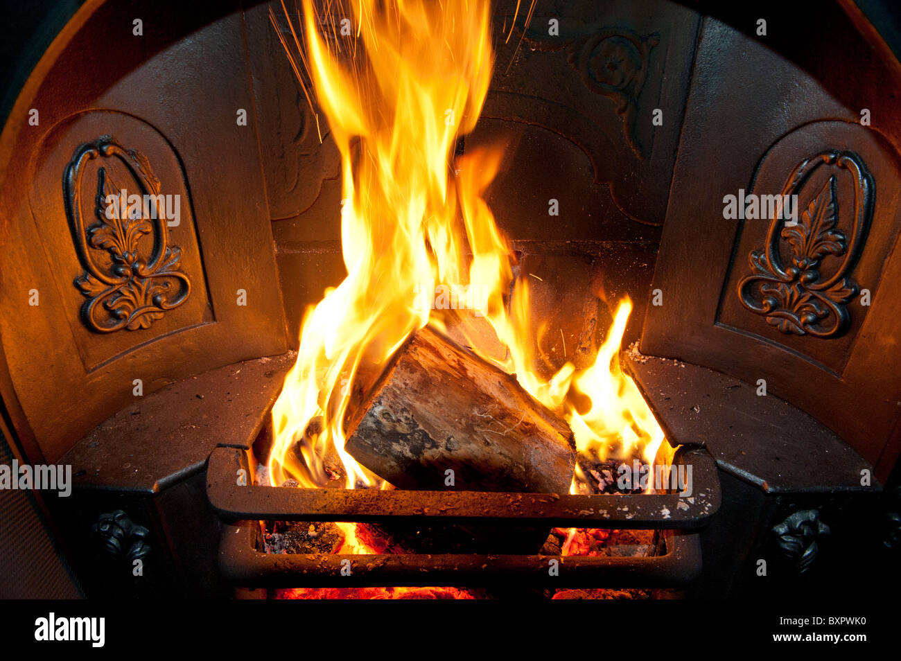 Logs burning brightly in an ornate Victorian or Edwardian fireplace hearth Stock Photo