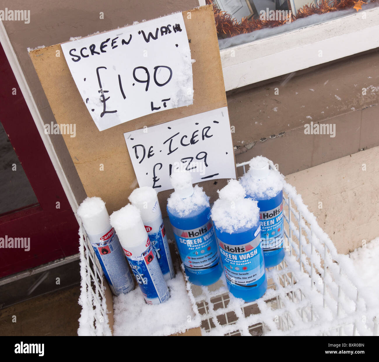 Last stocks of de-icer and antifreeze washer additive outside a shop in the UK during cold snap - snow on bottles Stock Photo