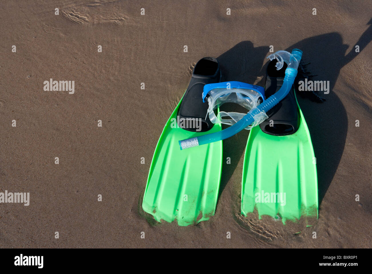 Snorkeling equipment (snorkel, mask and flippers) lying in wait on sandy beach. Stock Photo