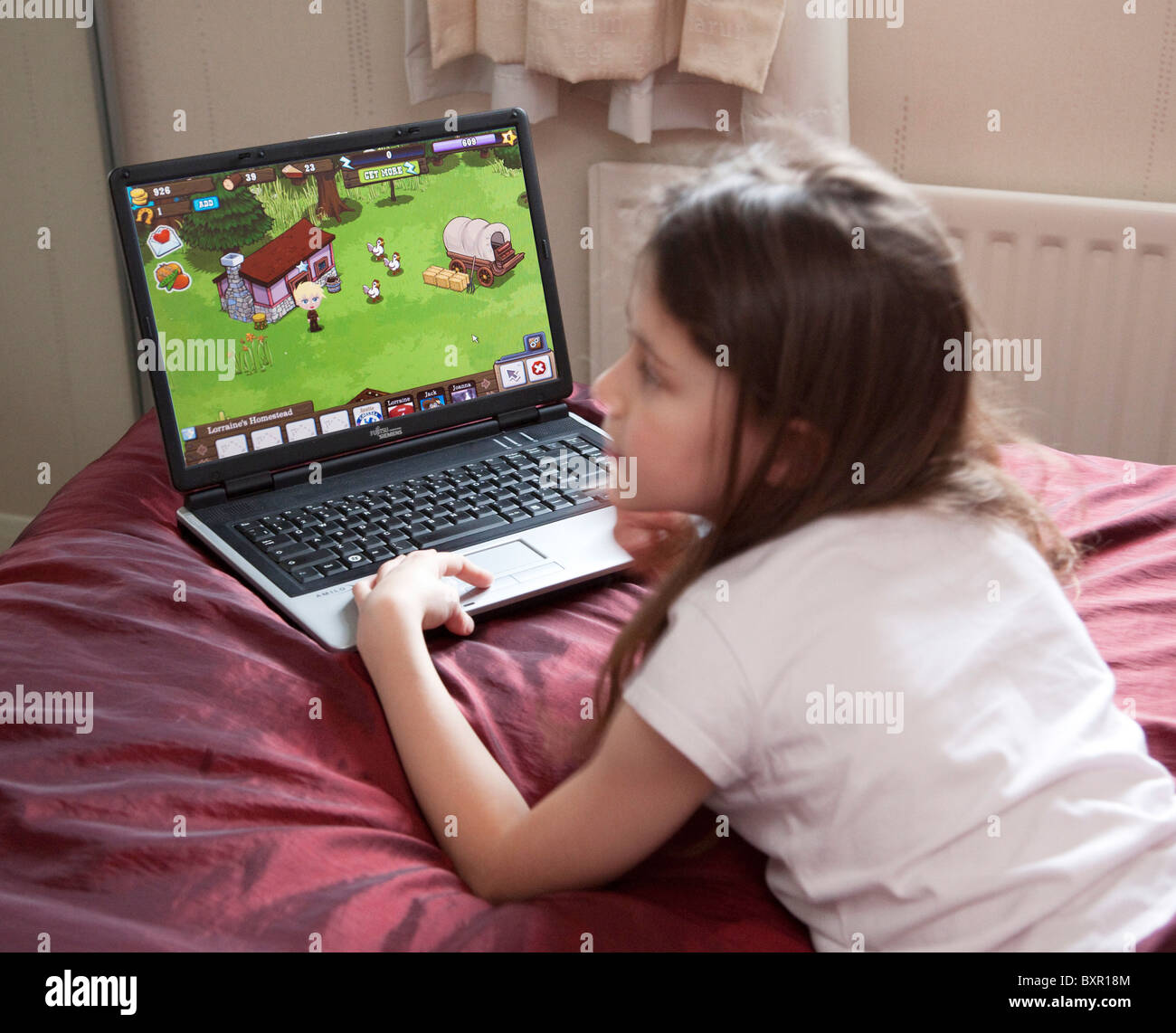 young girl playing FrontierVille game online with laptop computer Stock Photo