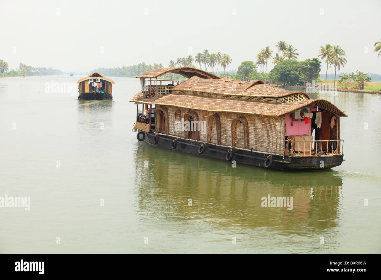 Thatched houseboats plying the Kerala Backwaters in India. River cruises are popular with foreign tourists and locals. Stock Photo