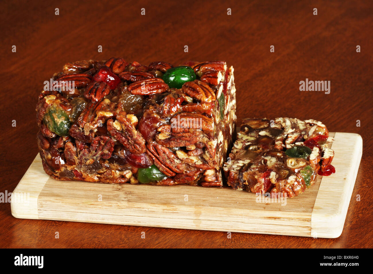 sliced holiday fruit cake on a wooden cutting board Stock Photo