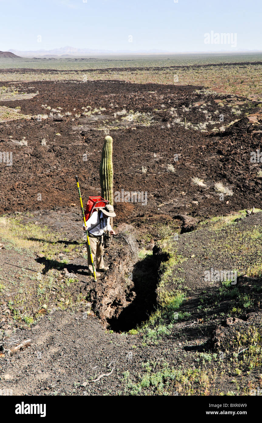 Geologist viewing small lava tube on side of Tecolote cinder cone, El Pinacate Biosphere Reserve, Sonora, Mexico Stock Photo