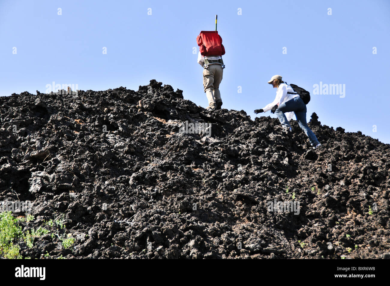 Hikers climbing rugged lava flow on side of Tecolote cinder cone, El Pinacate Biosphere Reserve, Sonora, Mexico Stock Photo