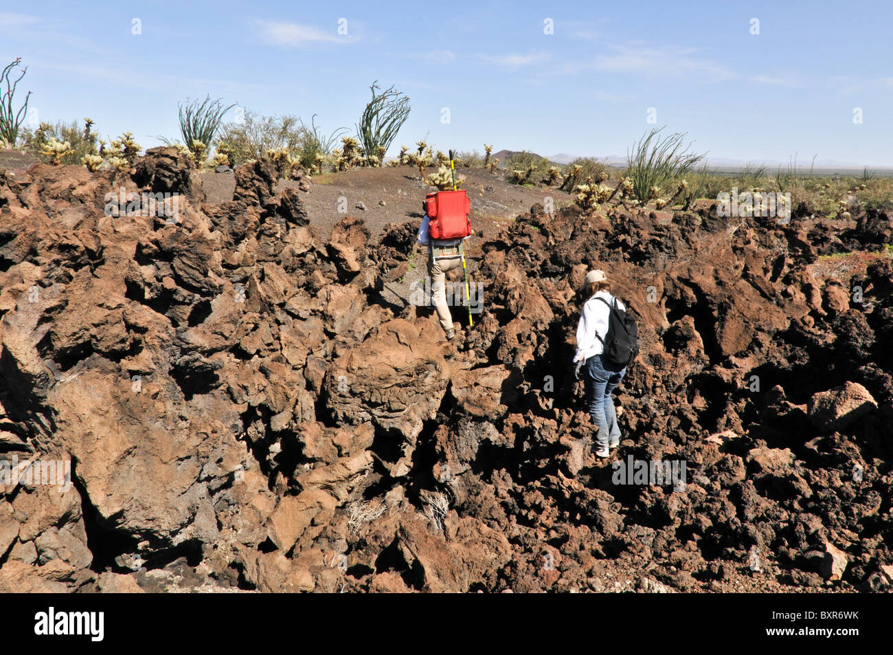Hikers traversing rugged lava flow on side of Tecolote cinder cone, El Pinacate Biosphere Reserve, Sonora, Mexico Stock Photo
