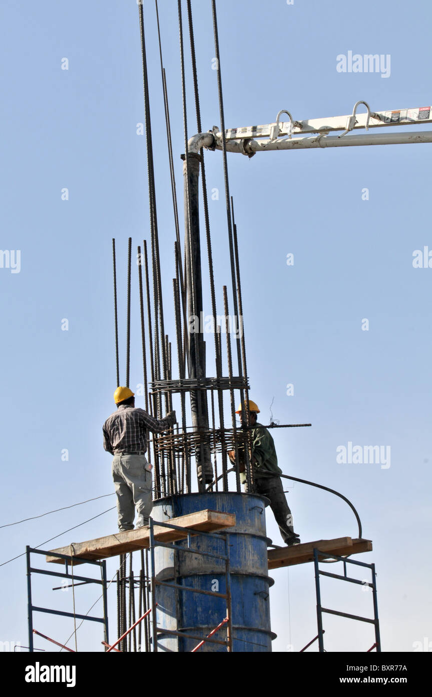 Workers pouring concrete in support post at construction site, Puerto