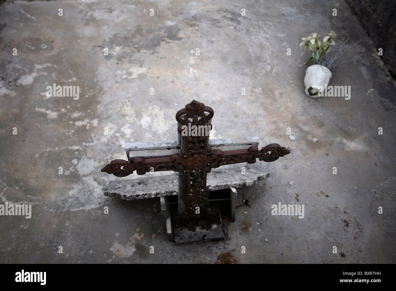 A concrete sealed grave site, fallen potted fake plant, view from