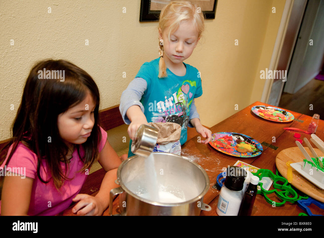 A Filipino/White 5yearold girl and her White friend measure sugar