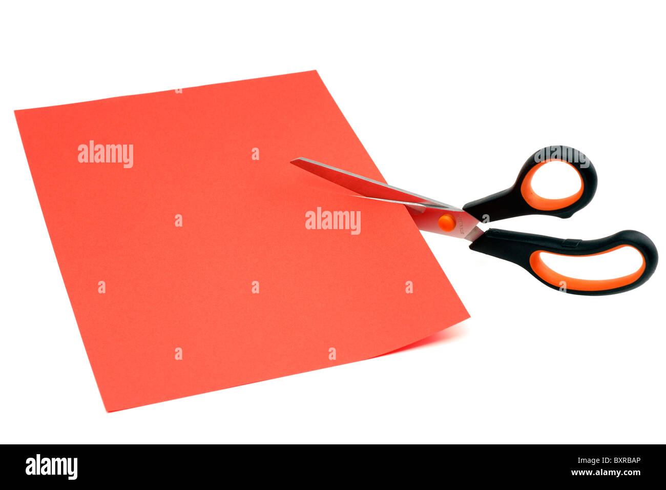 Scissors cutting through a sheet of red A4 paper Stock Photo