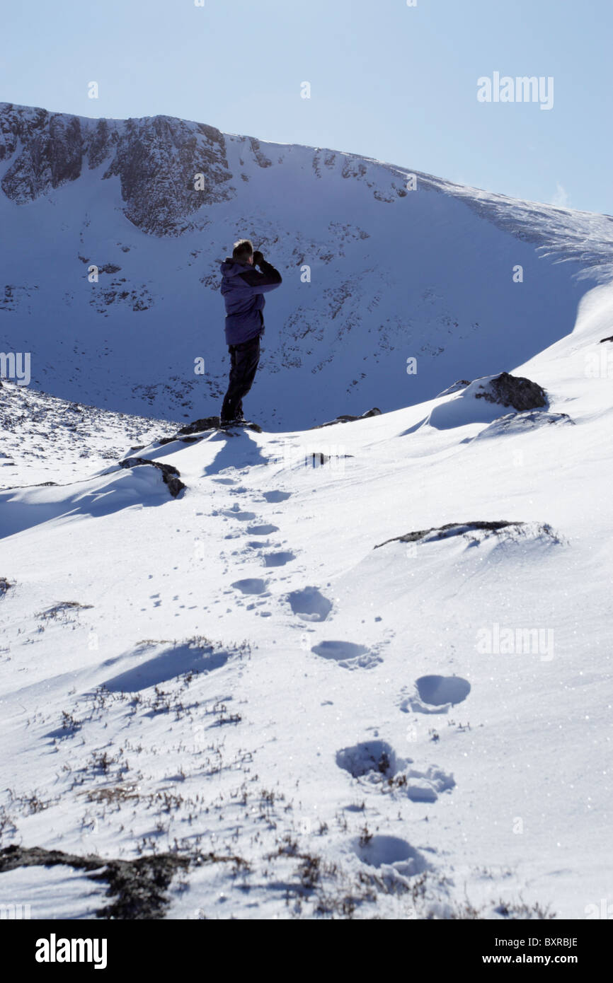 Birdwatcher looking for ptarmigan during winter in the northern corries of Cairngorm in the Scottish Highlands Stock Photo