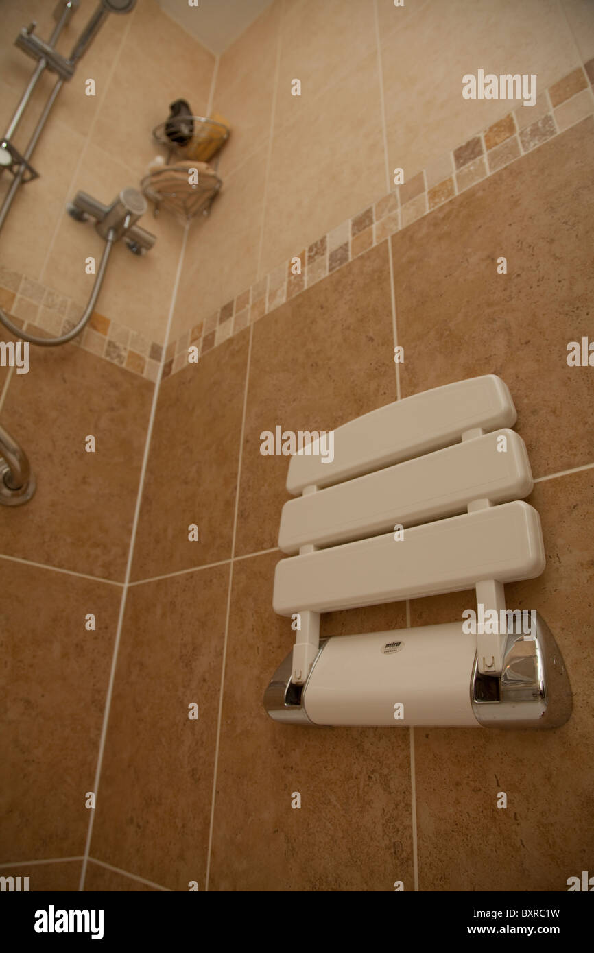 A disabled shower cubicle complete with chair and support handle bar in a residential property UK Stock Photo