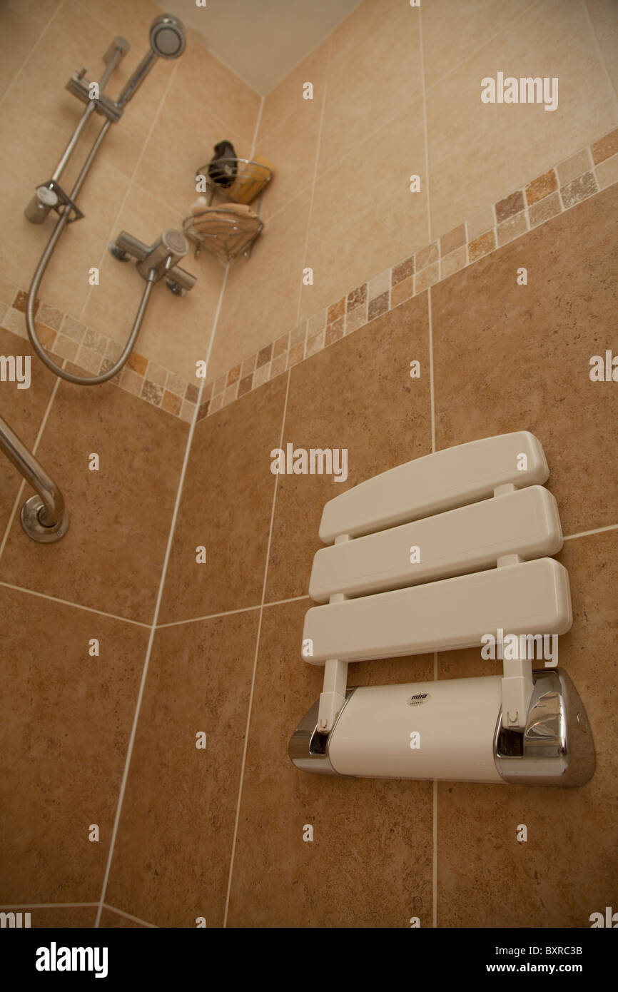 A disabled shower cubicle complete with chair and support handle bar in a residential property UK Stock Photo