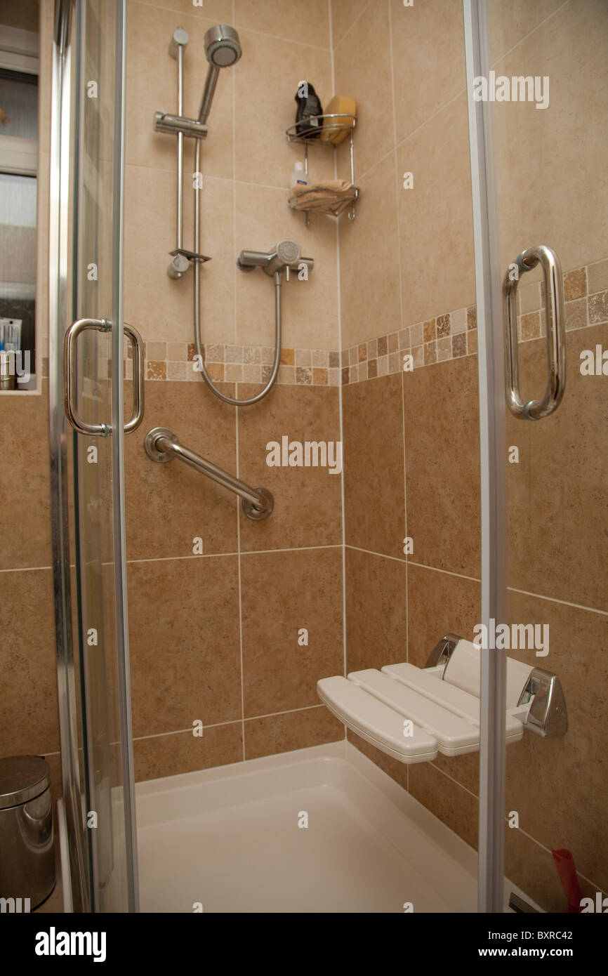 A disabled shower cubicle complete with chair and support handle bar in a residential property UK Stock Photo