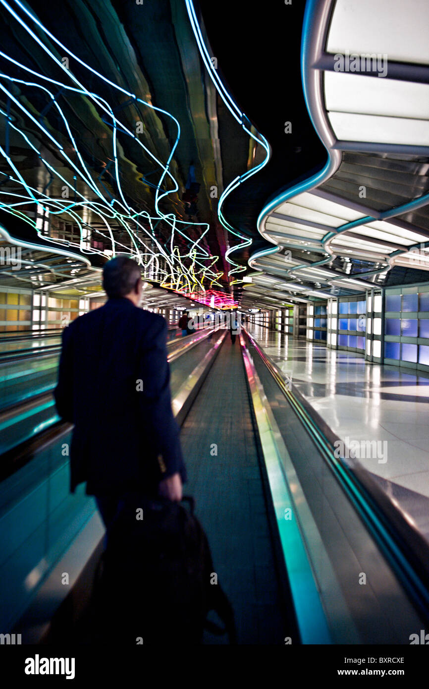 CHICAGO, ILLINOIS: Business traveler on the moving sidewalk with colored neon lights in Chicago O'Hare International Airport Stock Photo