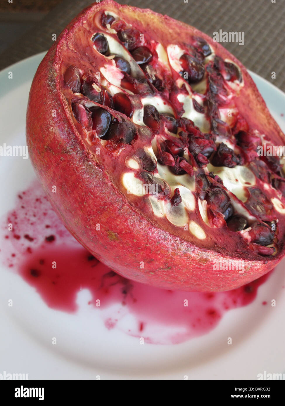 Old pomegranate on a white plate. Stock Photo