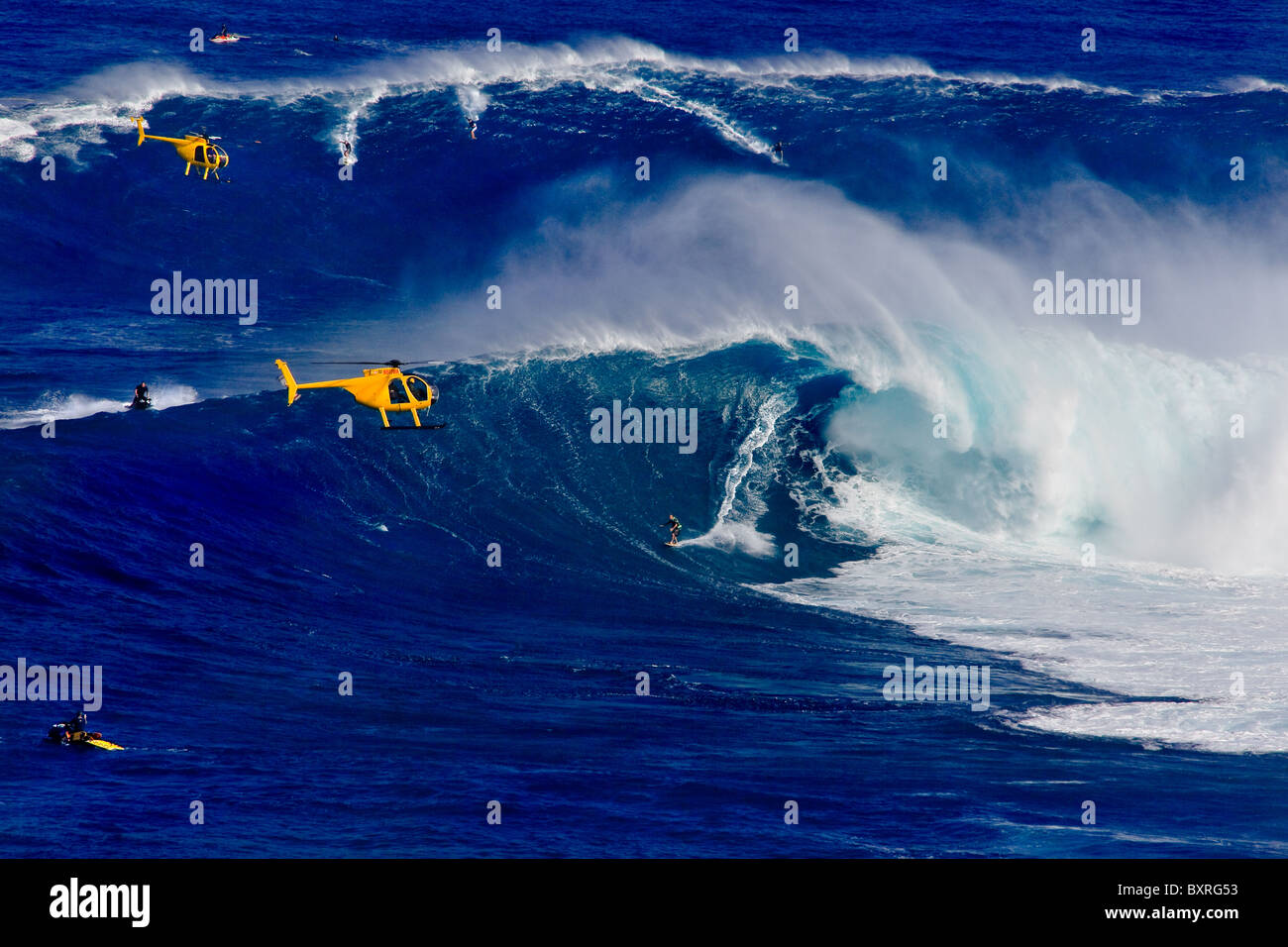Gigantic Waves in Maui with yellow helicopters at Peahi,  Also known as 'Jaws'.  World famous tow-in surf spot in Hawaii Stock Photo