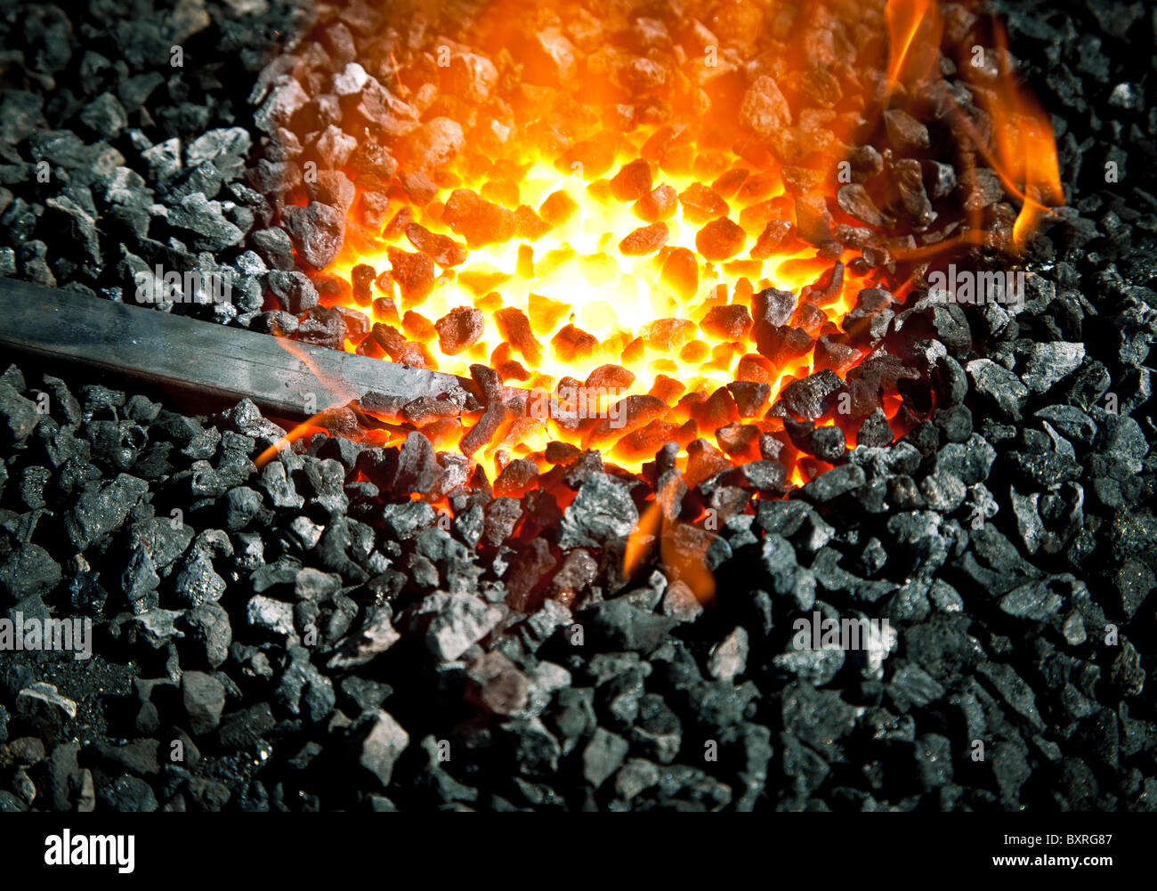 Old-fashioned blacksmith furnace with burning coals (focus is on the iron) Stock Photo