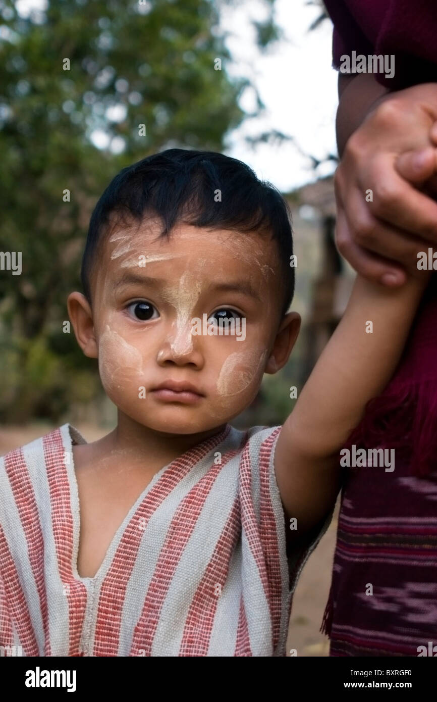 A young Burmese boy whose family fled war atrocities in Burma is holding his mother's hand in Ban Tha Ta Fang, Thailand.. Stock Photo