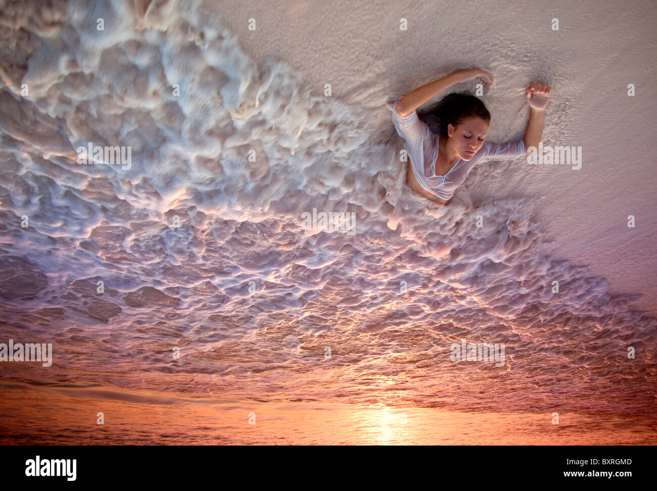 Young woman lying in surf on beach at sunset Stock Photo