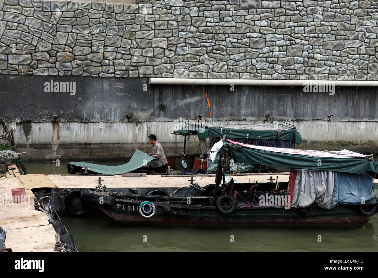 Local sampan owner tidies up where docked, near Pier 16, Macau Stock Photo