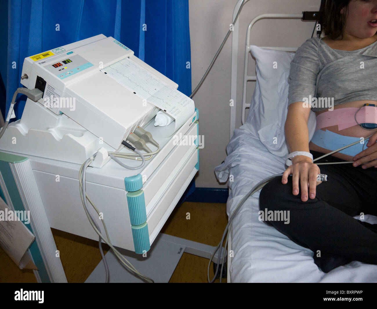 External fetal heart monitoring is performed by attaching external transducers to the mother's abdomen with elastic straps. Stock Photo