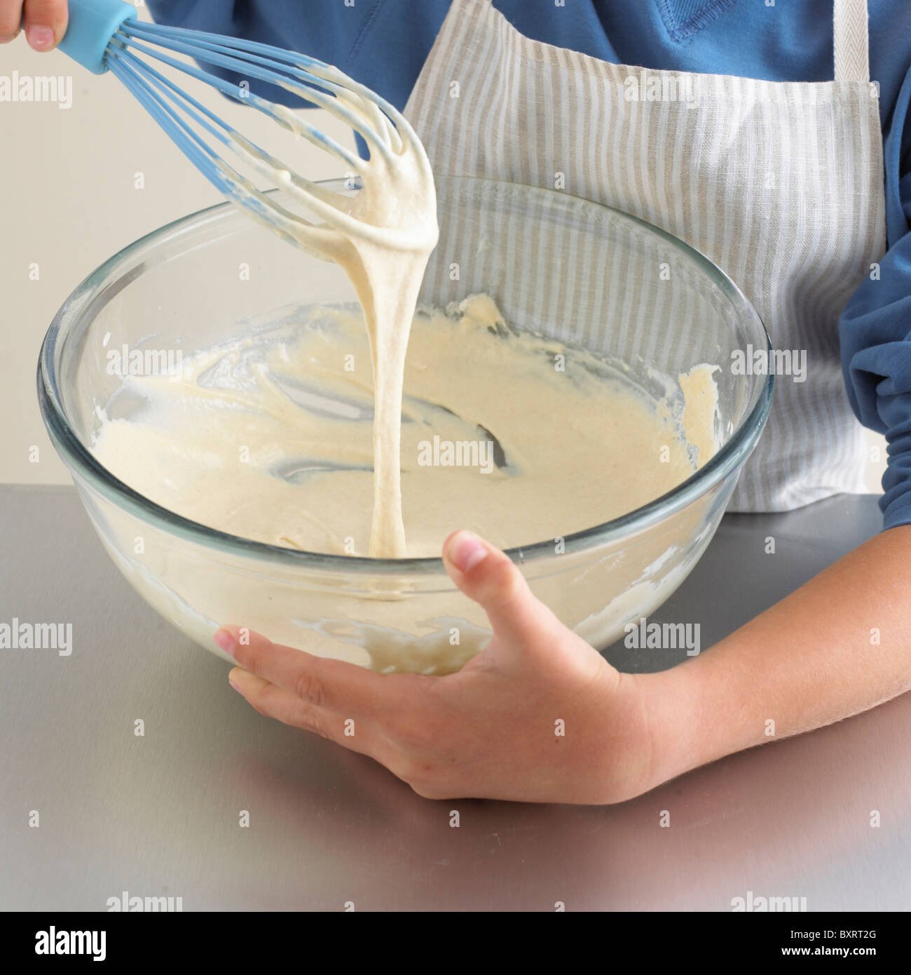 Boy's hands using a whisk to beat pancake batter in bowl Stock Photo