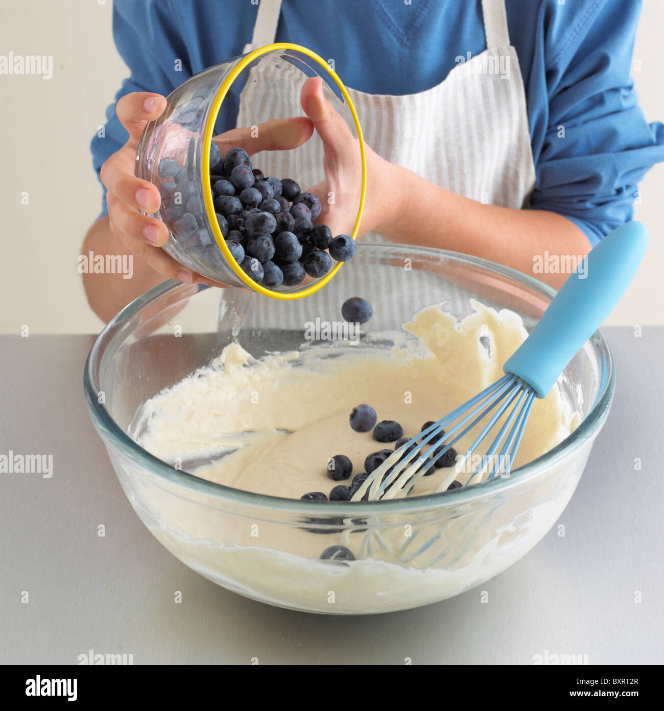 Boy's hands adding blueberries to pancake batter Stock Photo
