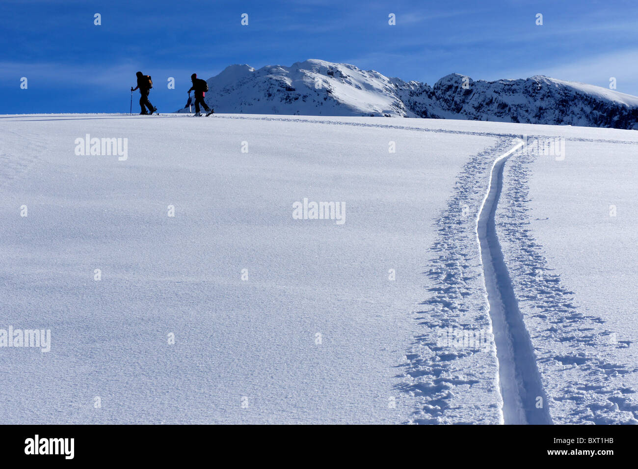 Skiers ascending mountain ridge in deep powder snow, Maennig-Stand, Diemtigal, Swiss Alps Stock Photo