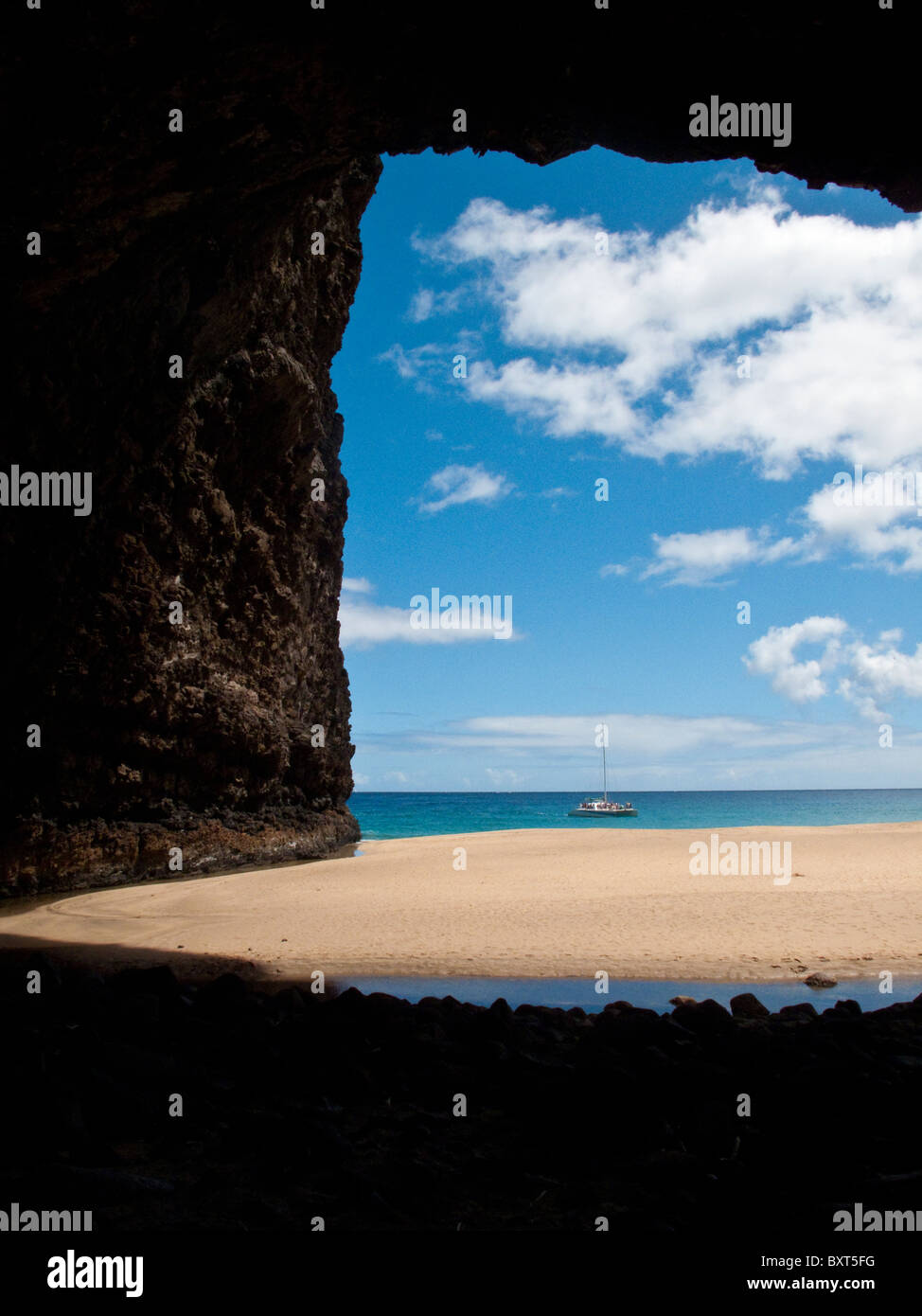 Sailboat anchored near arch at Honopu beach, Na Pali coast, Kauai Stock