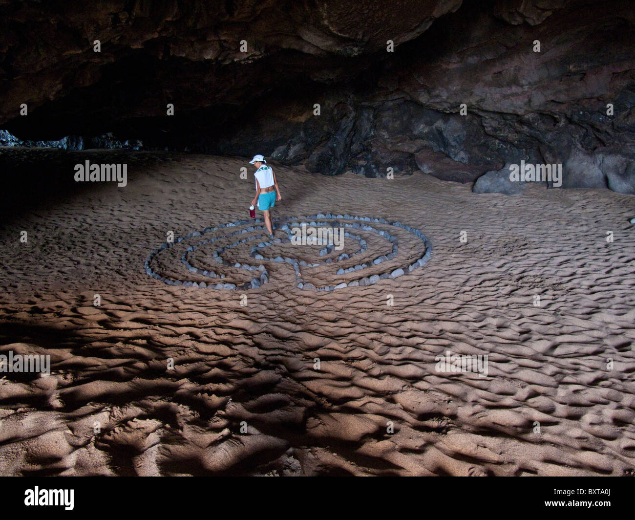 Woman walking in rock labyrinth on white sand in a cave near Kalalau beach, Na Pali coast, Kauai Stock Photo