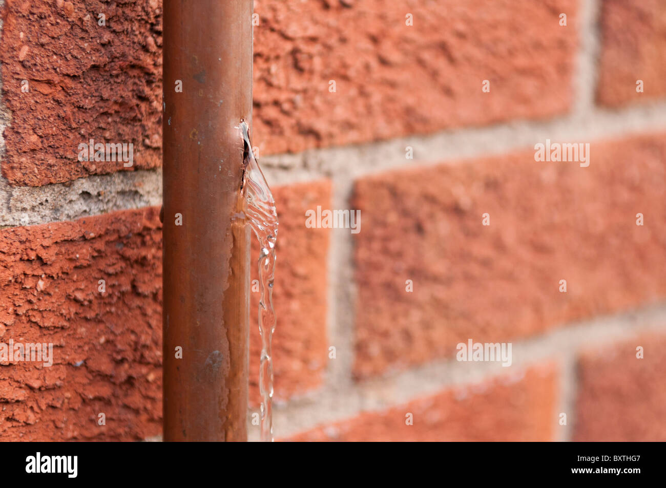 Water coming out of a burst copper water pipe which had been broken by freezing ice Stock Photo